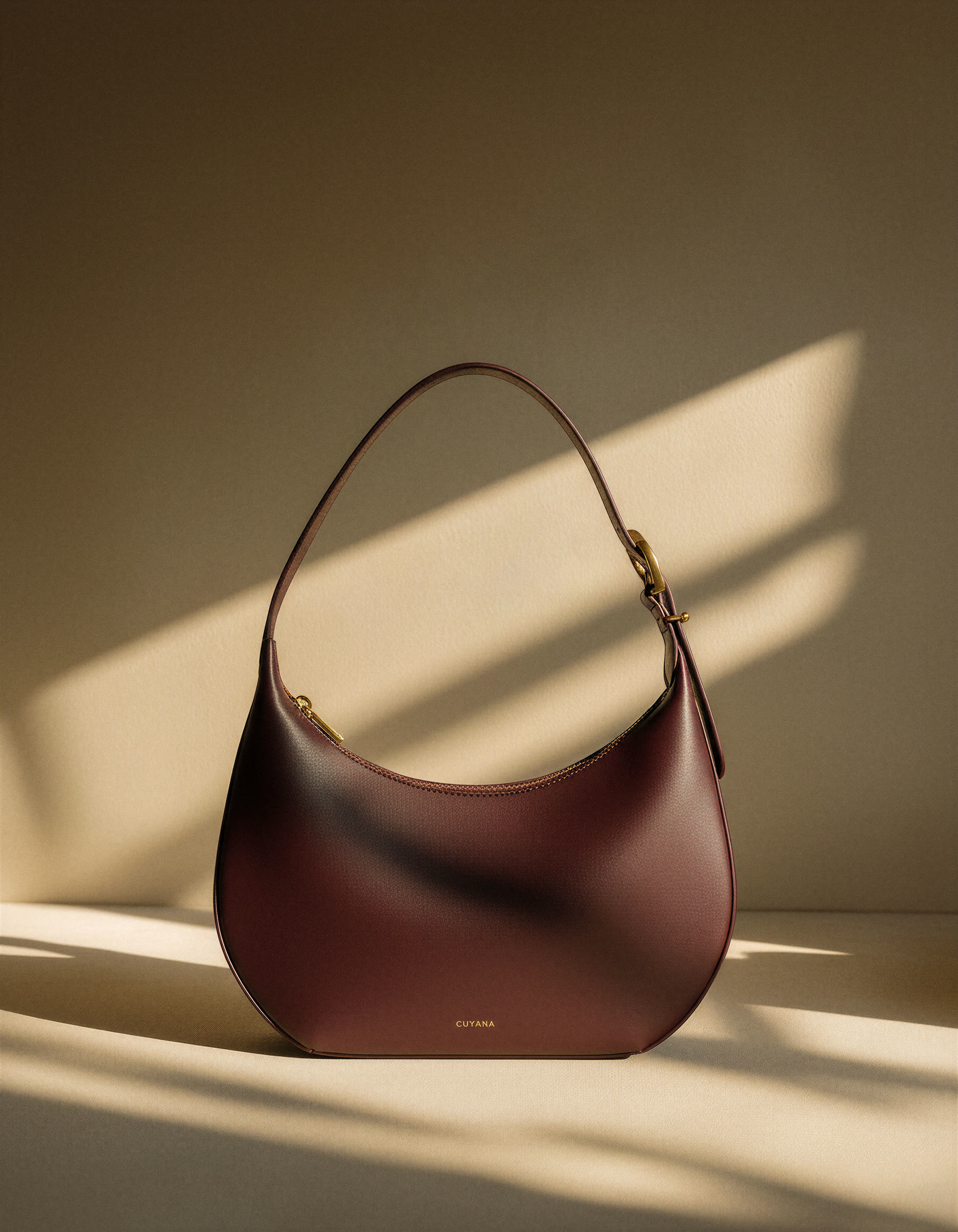 Cuyana burgundy leather bag in raking window light